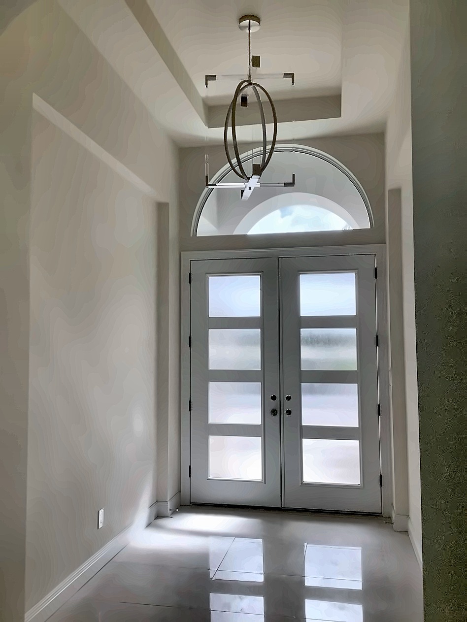 Foyer with frosted-glass double doors beneath an arched transom and a ring pendant in an acrylic frame