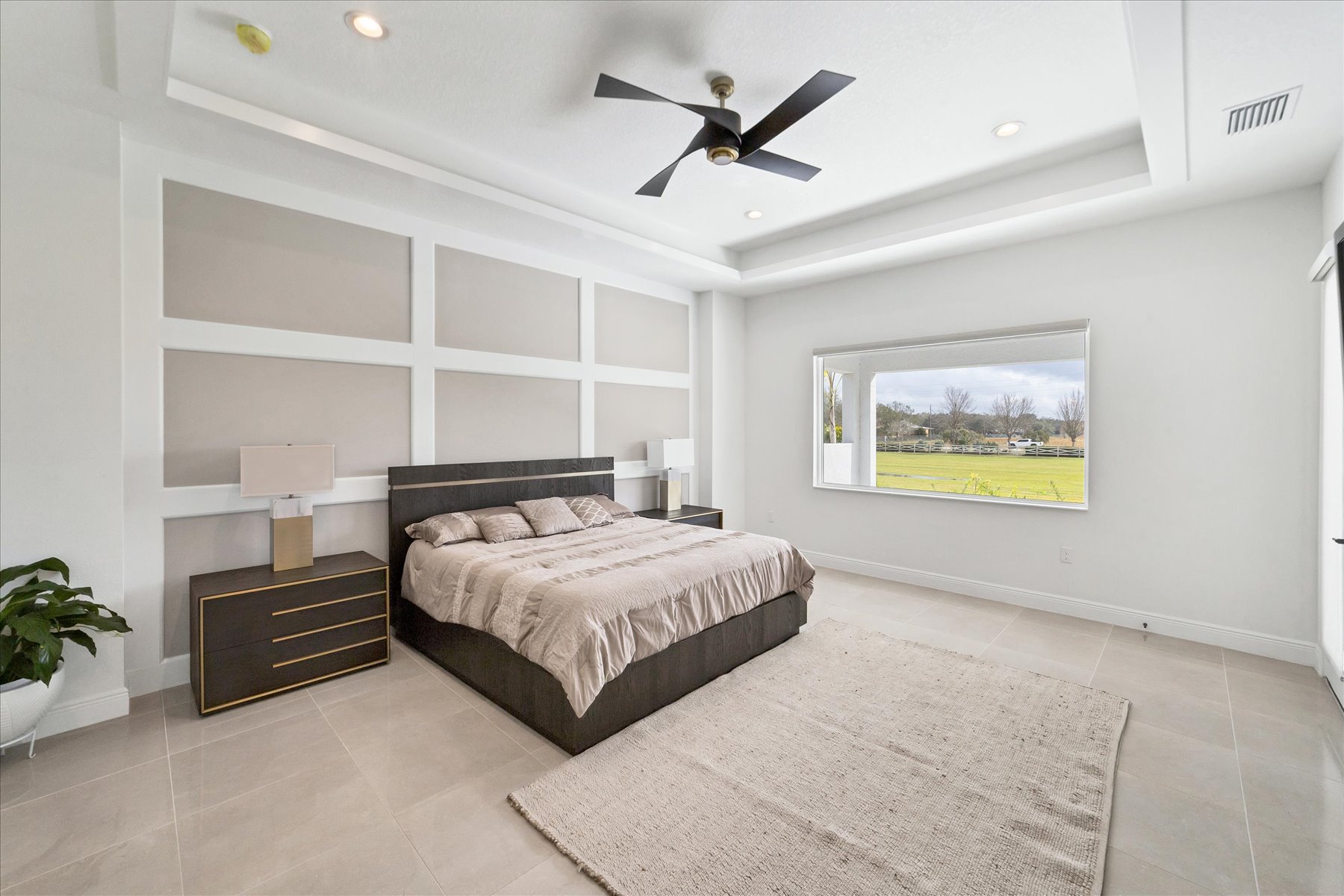 Primary bedroom with a paneled taupe accent wall, dark wood bed and gold-trimmed nightstands