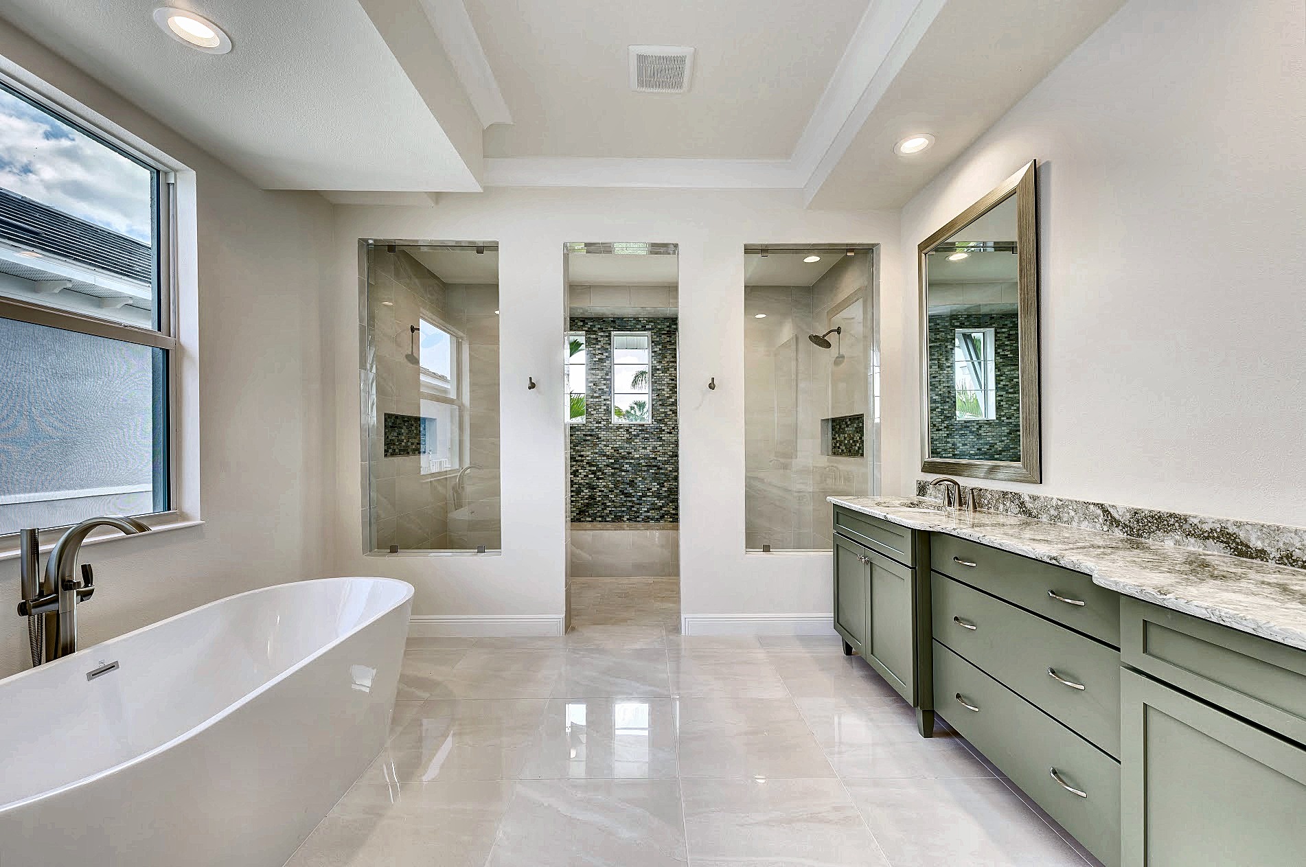 Primary bath with a freestanding tub, glass showers and a sage green vanity