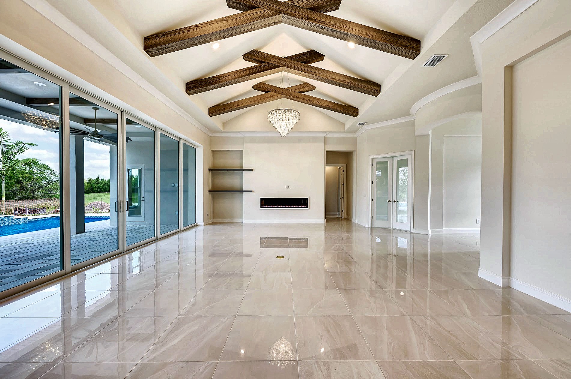 Great room with a vaulted beamed ceiling, linear fireplace and a wall of sliding glass doors