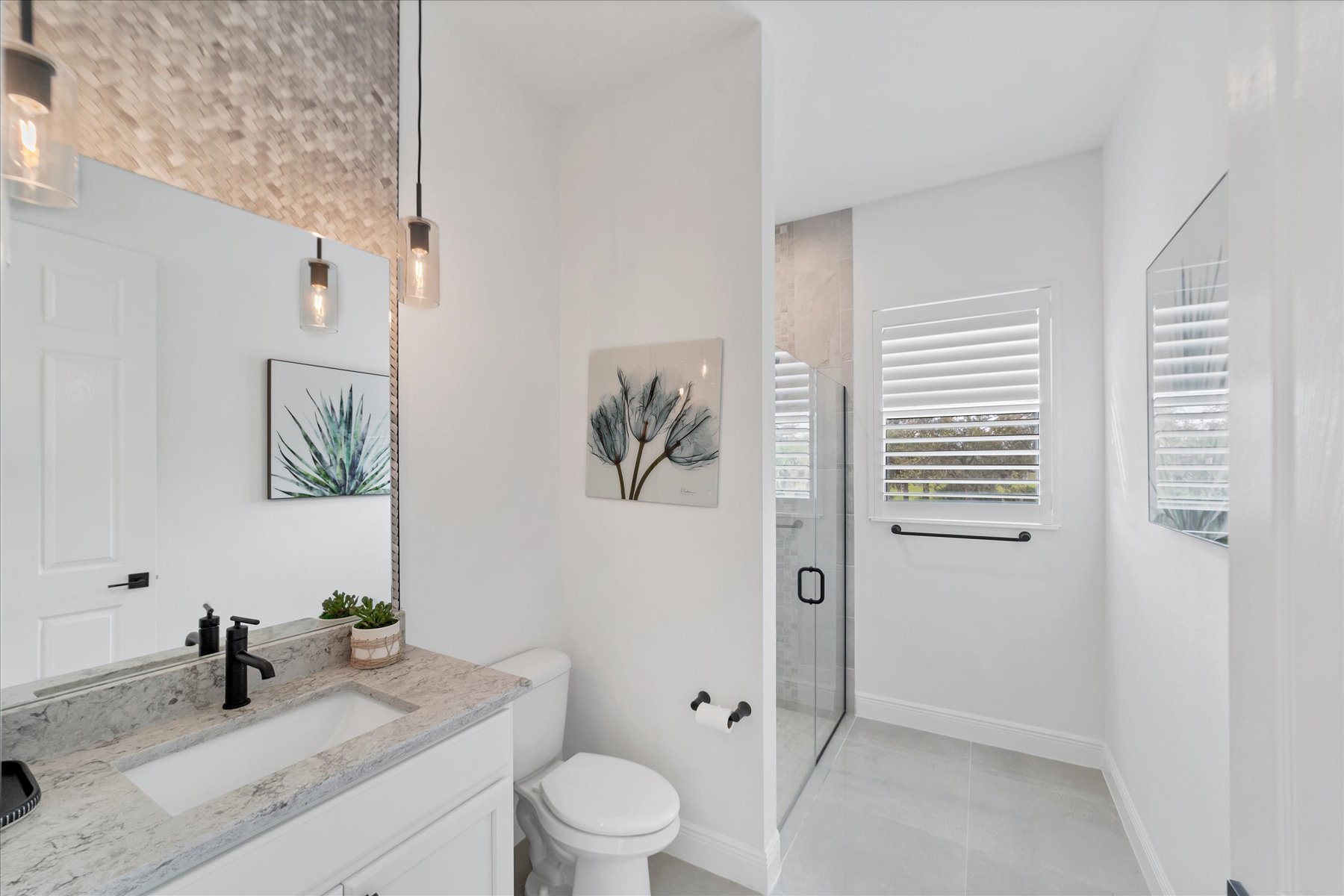 Airy guest bathroom with woven mosaic accent tile, veined stone counter and botanical art
